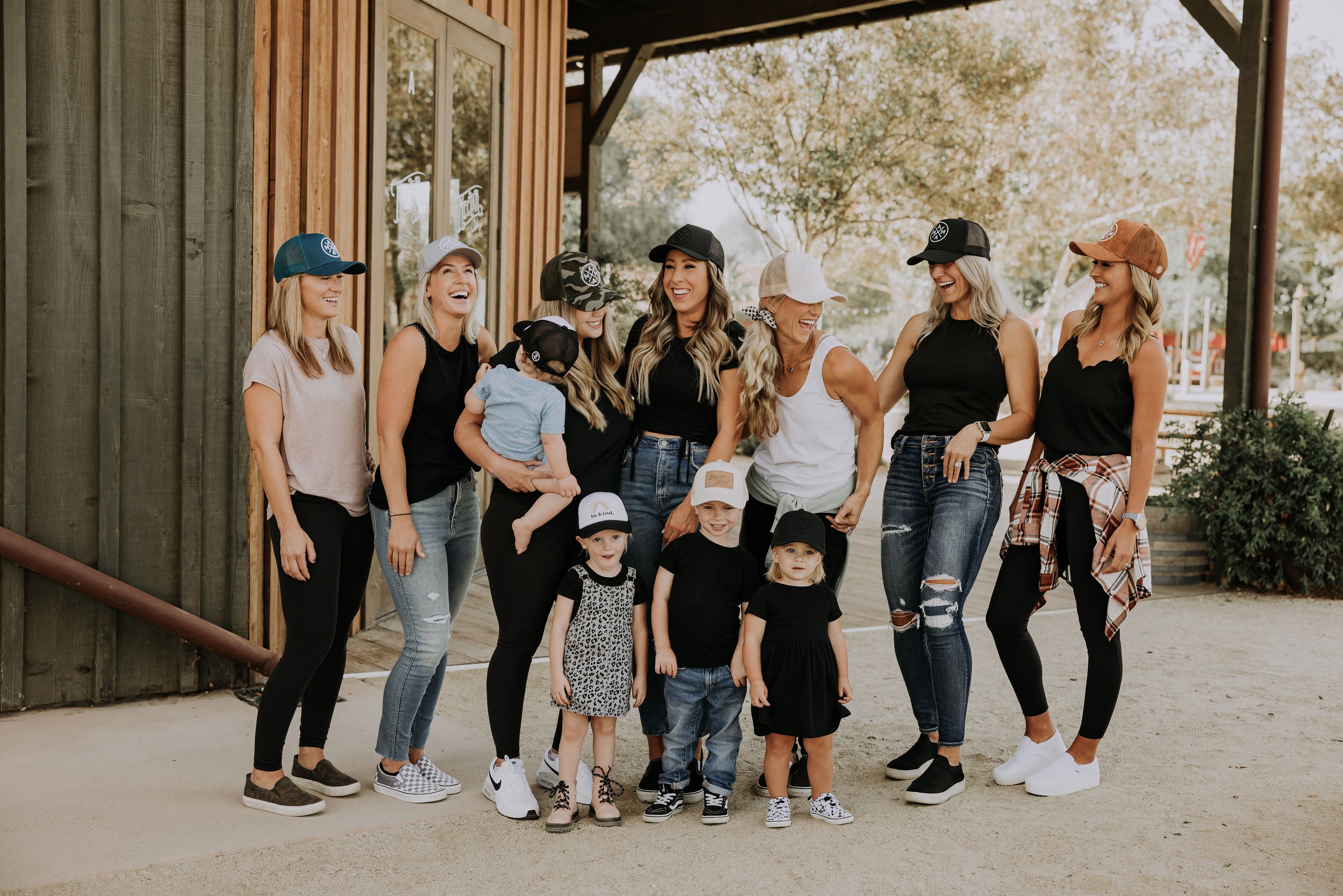 group of Moms wering hats and their kids laughing standing in a rustic sandy area