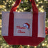 The Mama Claus Tote Bag by Mama X™ Brand is a festive cotton canvas bag with red handles and “Mama Claus” lettering plus a Santa hat—perfect as a holiday errand bag.