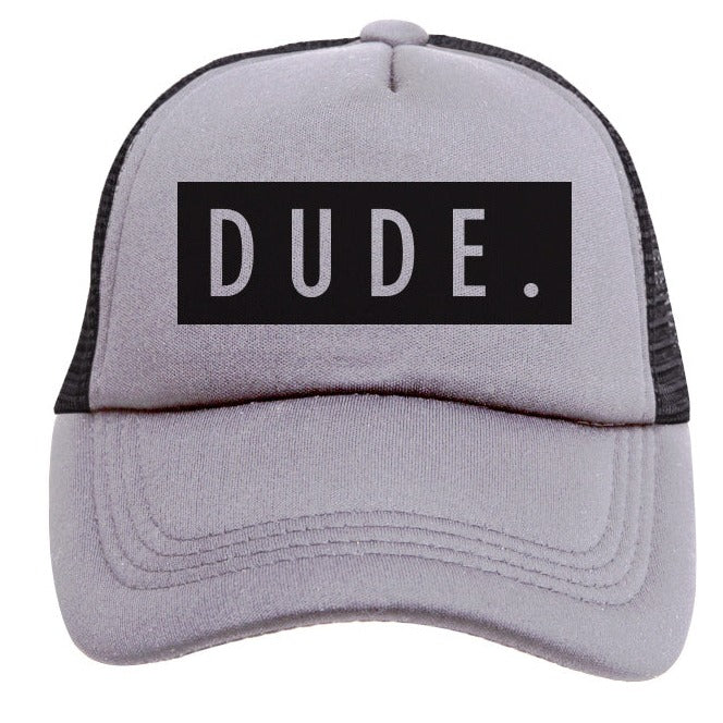 The Mama X™ Brand DUDE Trucker Hat - Grey &amp; Black features a gray 5-panel design with a black mesh back and a bold white "DUDE." printed on a black rectangular patch on the front, complete with an adjustable snap for a comfortable fit.