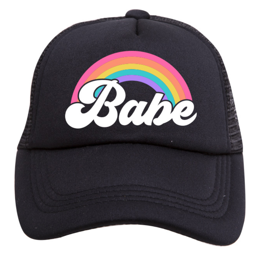 The Rainbow Babe Trucker Hat from Mama X™ Brand is a black 5-panel cap featuring the word "Babe" in white, stylized cursive letters. Above the text, there&